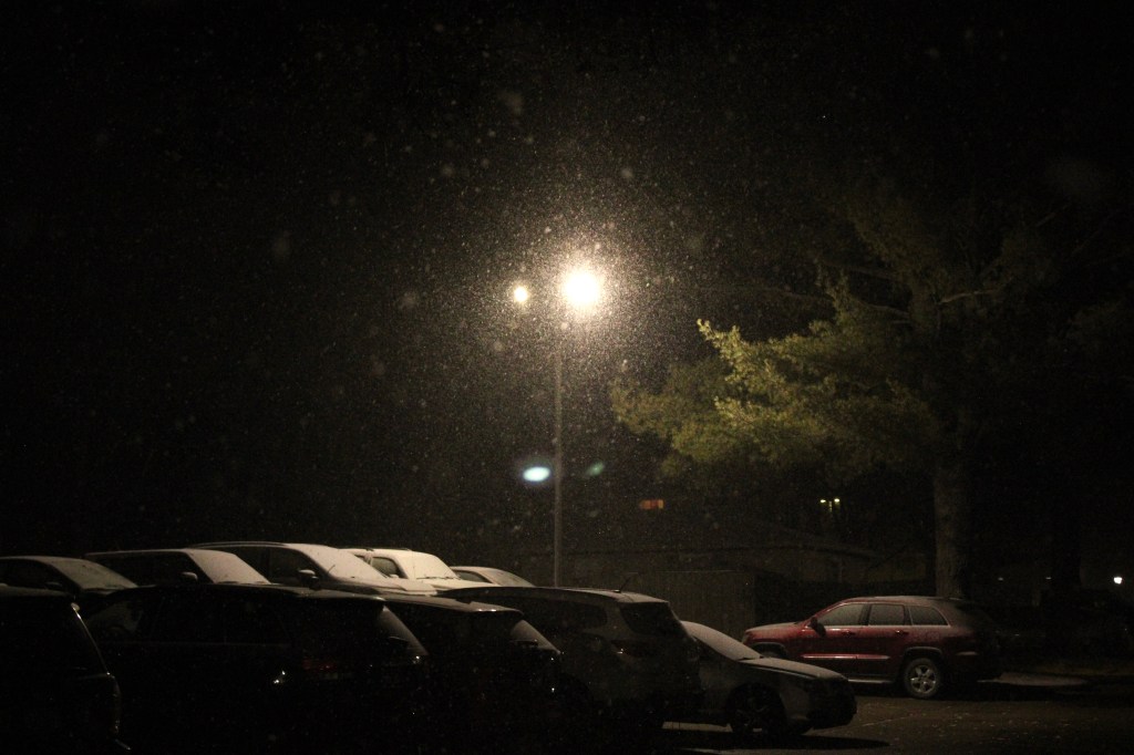 Photograph of a parking lot during a snowfall with sodium lamp in center frame